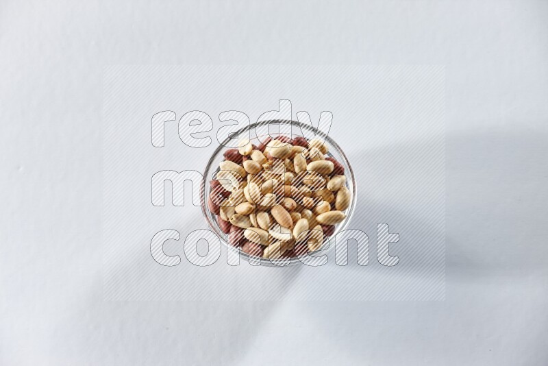 A glass bowl full of peeled peanuts on a white background in different angles