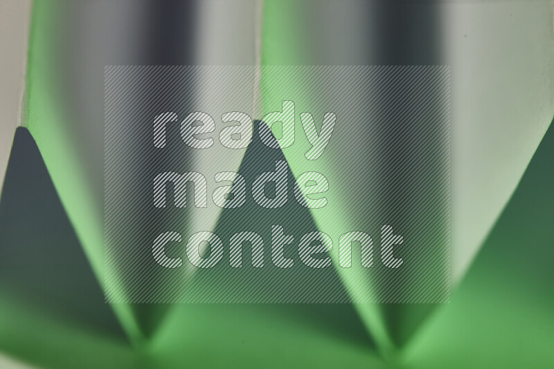 A close-up abstract image showing sharp geometric paper folds in white and green gradients