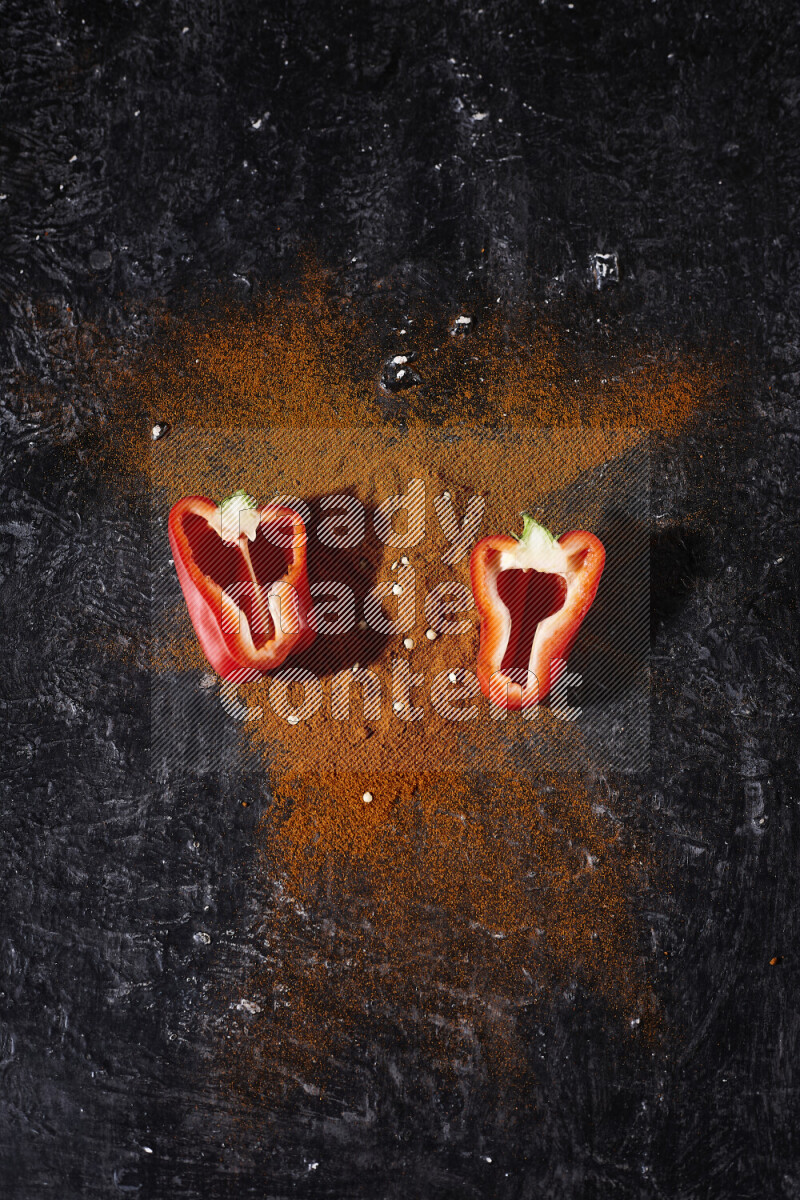 حفنة من بودرة البابريكا مع نصفين من الفلفل الأحمر الحلو على خلفية سوداء