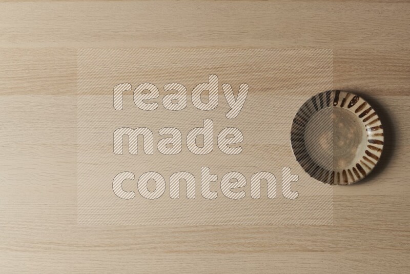 A multicolored pottery plate on light wooden background