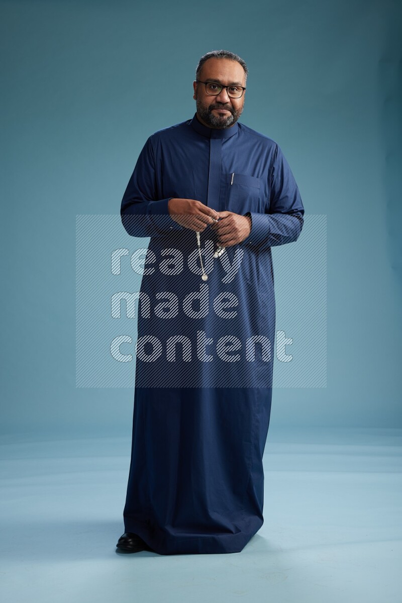 Saudi Man without shimag Standing Interacting with the camera on blue background