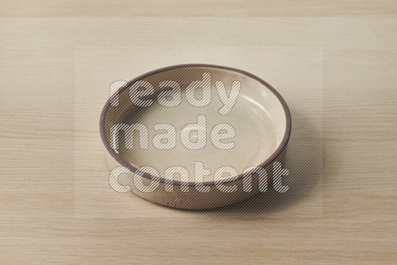 A beige pottery oven bowl on light wooden background