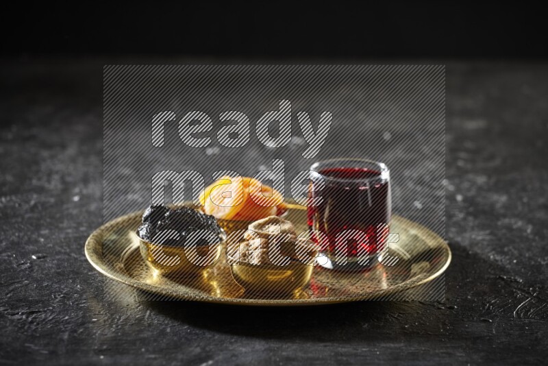 Dried fruits in metal bowls with Hibiscus on a tray in dark setup