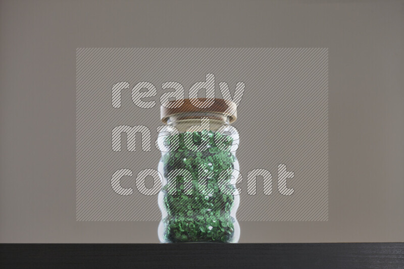 Sequins in a glass jar on black background