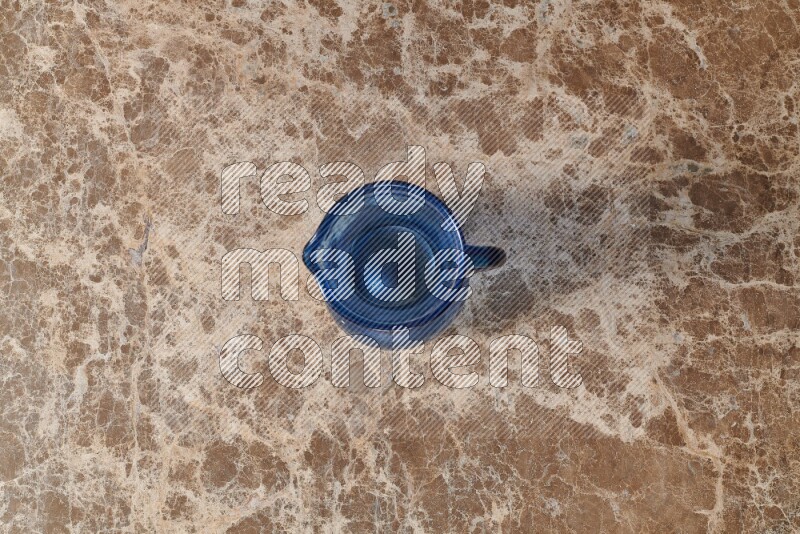 A colored glass jug on beige marble background