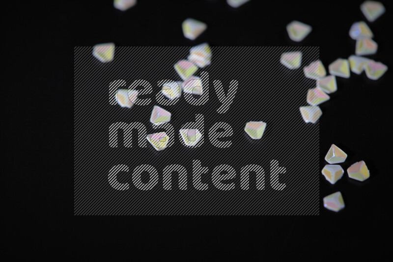 Colorful plastic shards for decoration scattered on a black background