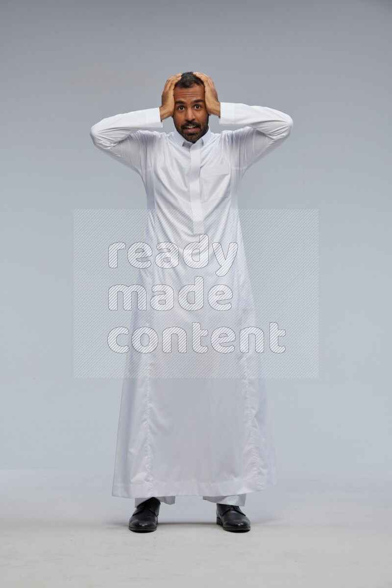 Saudi man Wearing Thob standing interacting with the camera on Gray background