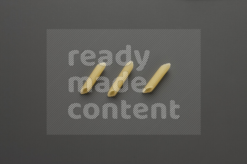 Mini penne pasta on grey background