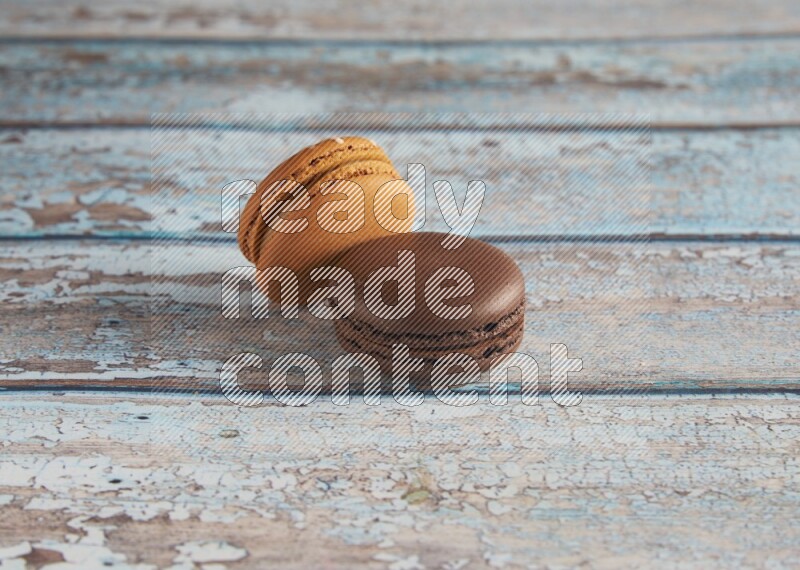 45º Shot of of two assorted Brown Irish Cream, and Brown Dark Chocolate macarons on light blue background