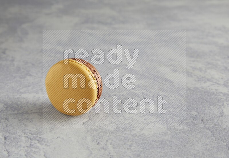 45º Shot of Yellow and Brown Chai Latte macaron on white  marble background