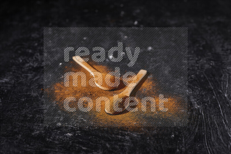 ملعقتان خشبيتان كلاهما ممتلئ ببودرة البابريكا علي خلفية سوداء