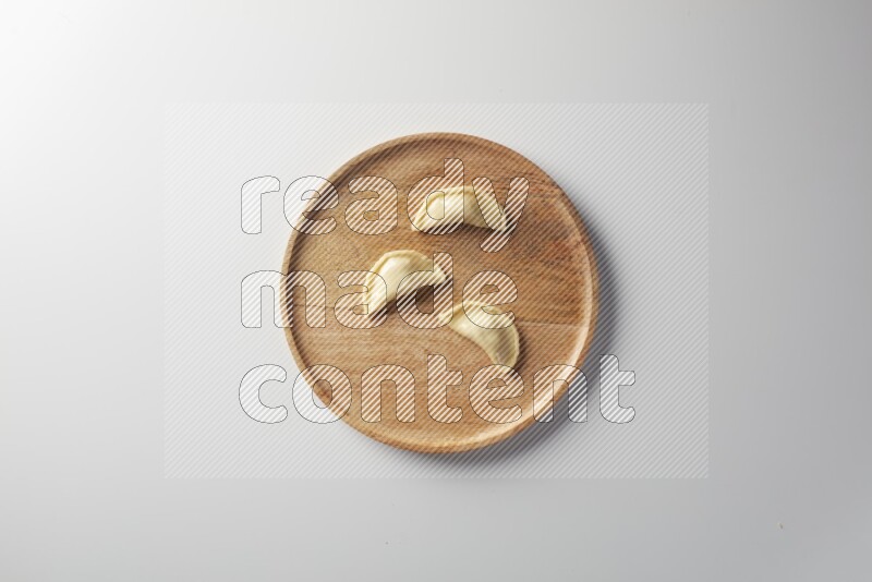Three Sambosas on a wooden round plate on a white background