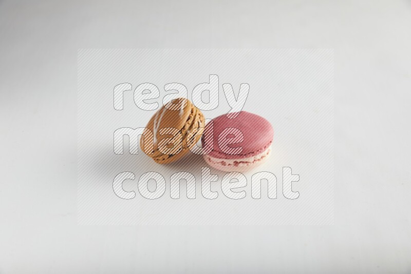 45º Shot of of two assorted Brown Irish Cream, and Pink Litchi Raspberry macarons on white background