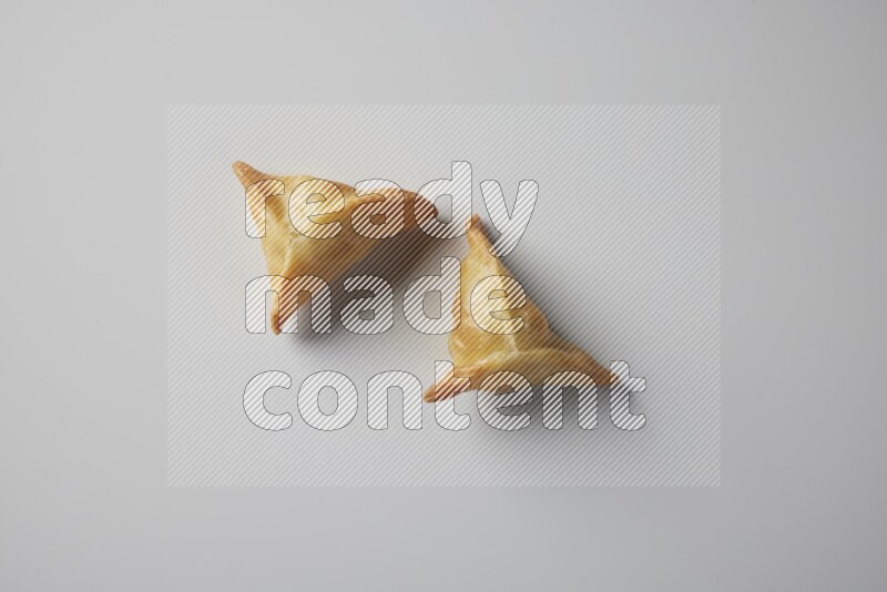 Two fried sambosa from a top angle on a white background