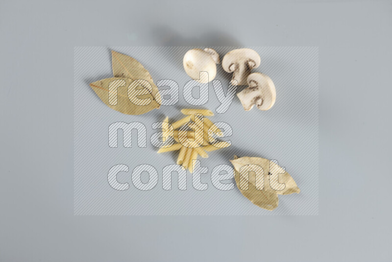 Raw pasta with different ingredients such as cherry tomatoes, garlic, onions, red chilis, black pepper, white pepper, bay laurel leaves, rosemary, cardamom and mushrooms on light blue background