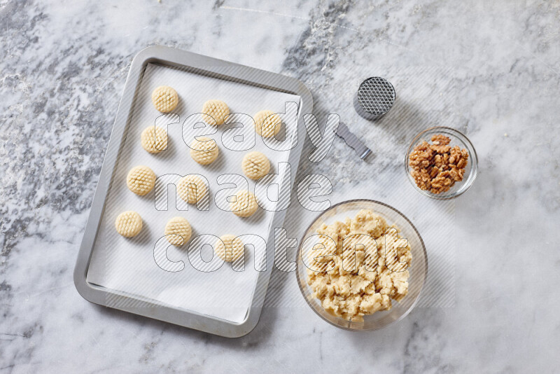 كحك خطوة بخطوة بمكوناته سمن، سكر، دقيق، سمسم، خميرة، ماء ونكهة الكحك على خلفية رخام رمادي