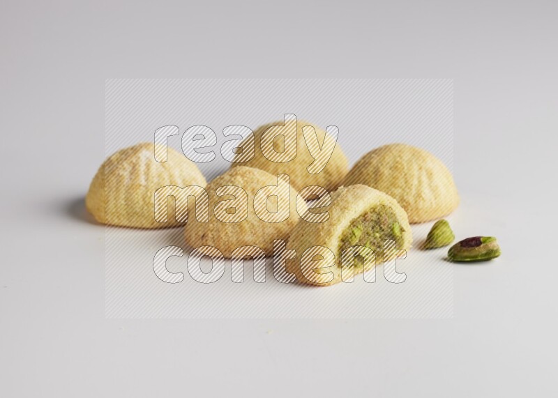 Five Pieces of Maamoul filled with pistachio  paste one of them is cut direct on white background