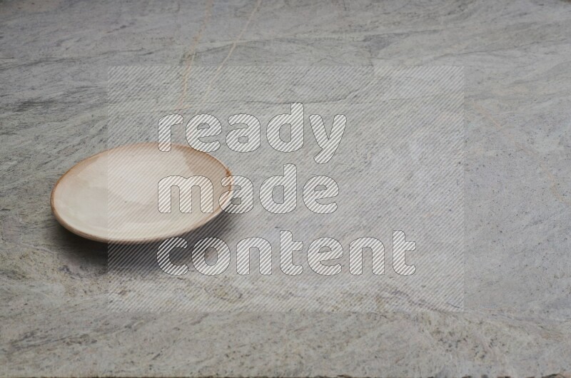 A beige pottery plate on grey marble background