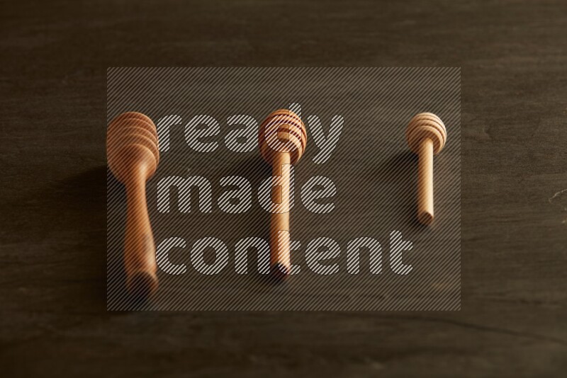 Wooden honey dipper on black slate background