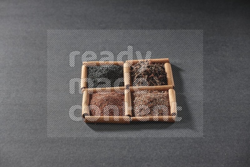 4 squares of cinnamon sticks full of black seeds, garden cress, flaxseeds and cloves on black flooring