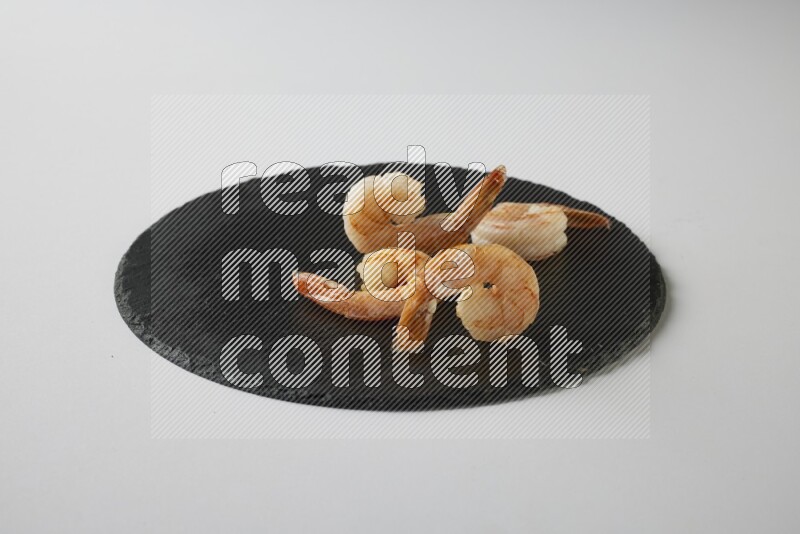 four grilled shrimp  on a black slate direct  on a white back ground
