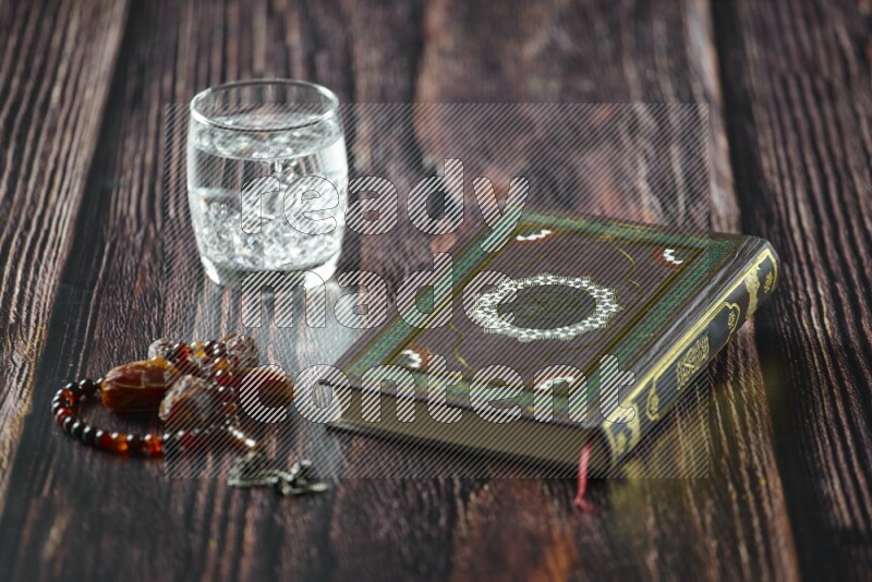 Quran with dates, prayer beads and different drinks all placed on wooden background