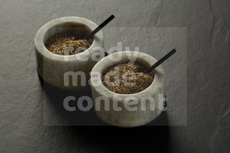 black and white round marble containers filled with herbs on gray textured countertop