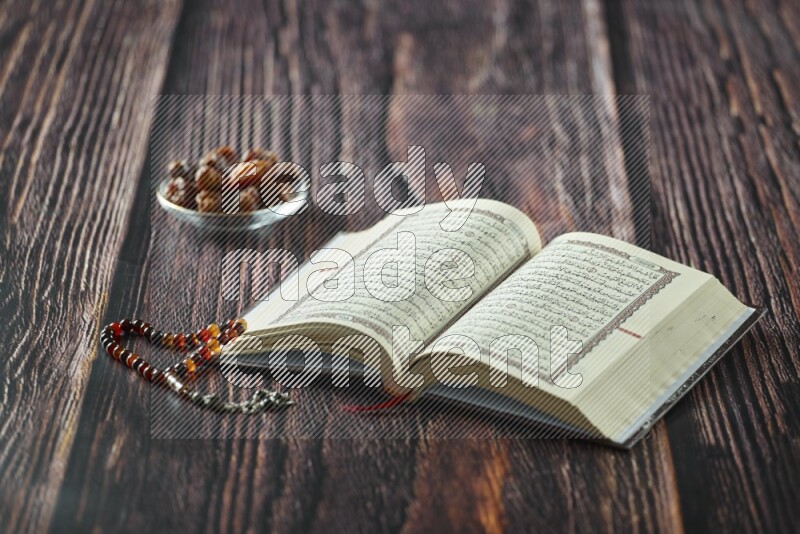 Quran with dates, prayer beads and different drinks all placed on wooden background