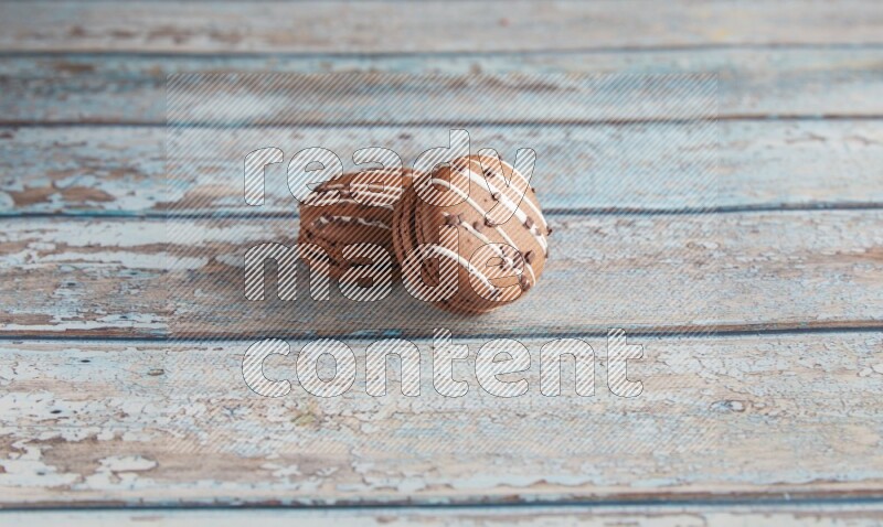 45º Shot of two Brown white  Chocolate Caramel macarons on light blue wooden background