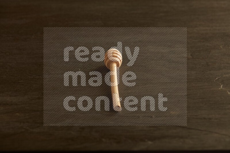 Wooden honey dipper on black slate background