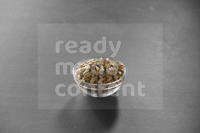 A glass bowl full of cardamom on black flooring