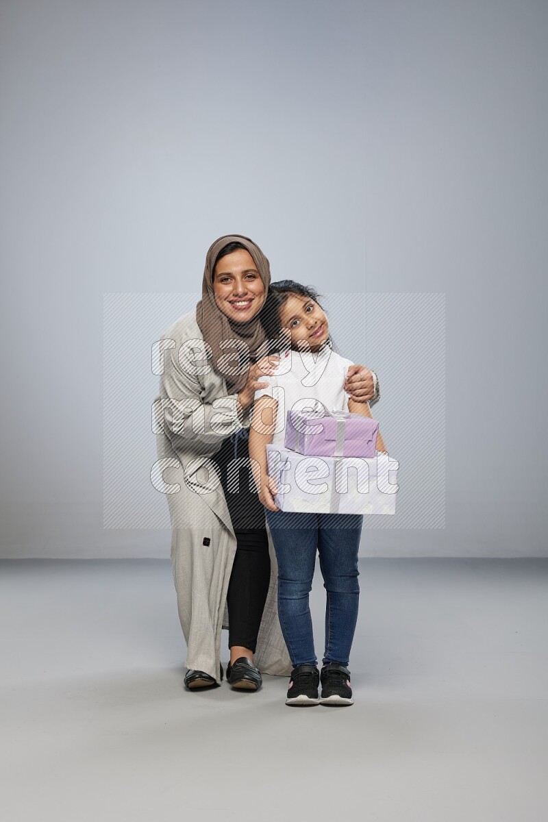 A girl giving a gift to her mother on gray background