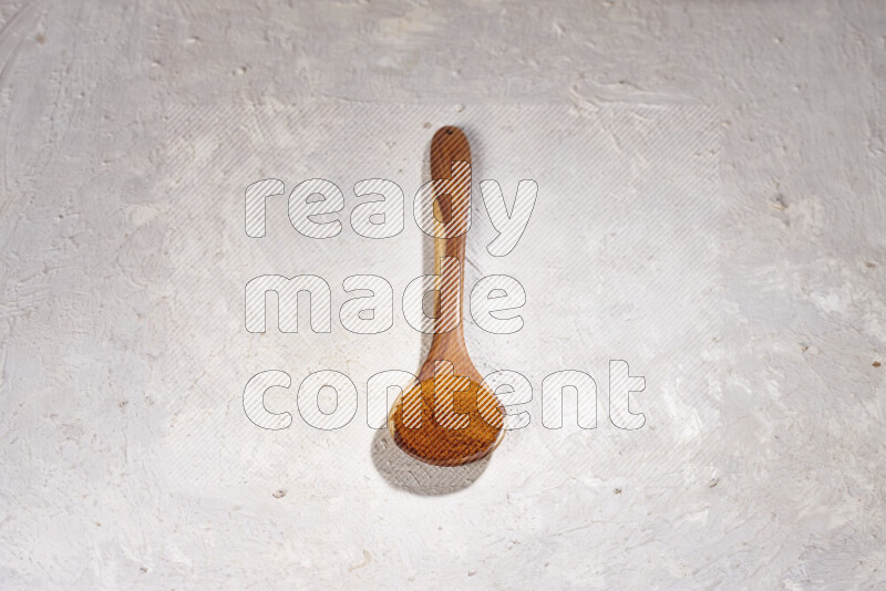A wooden ladle full of ground paprika powder on white background