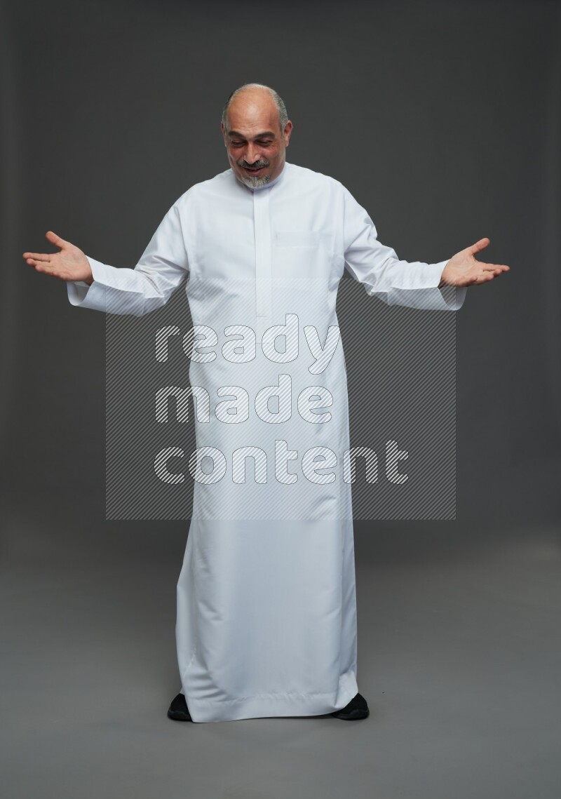Saudi man without shomag Standing Interacting with the camera on gray background