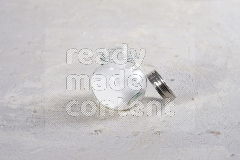 A glass jar full of fine table salt on white background