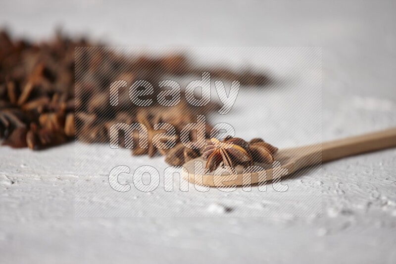 Star anise on a wooden spoon and spreading on the background on a white flooring