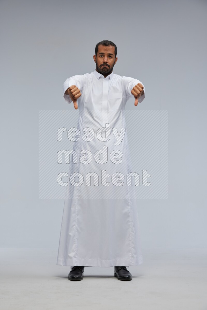 Saudi man Wearing Thob standing interacting with the camera on Gray background