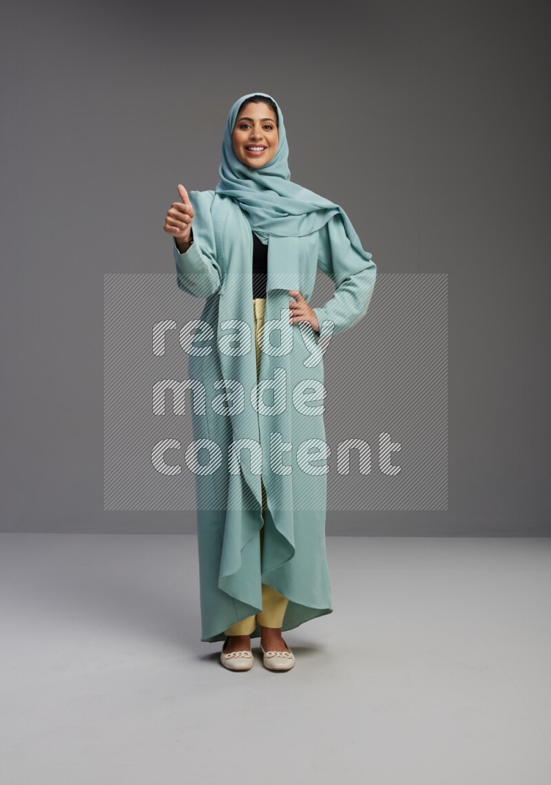 Saudi Woman wearing Abaya standing interacting with the camera on Gray background