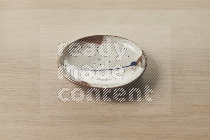 A multicolored pottery plate on light wooden background