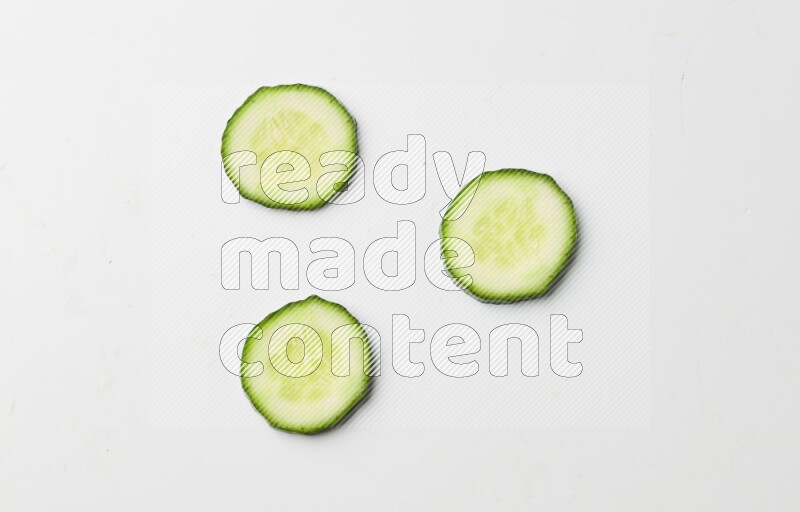 three cucumber slices on white background