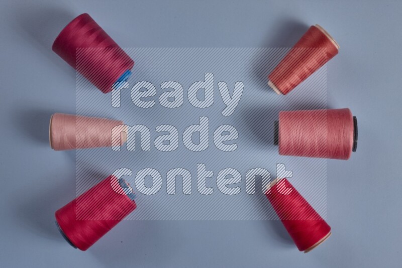 A pink collection of sewing and tailoring tools arranged on a blue background