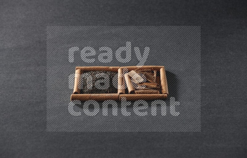 مربعان من أعواد القرفة ممتلئان بالشاي والقرفة علي خلفية سوداء