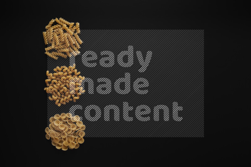 Different pasta types in 3 bunches on black background