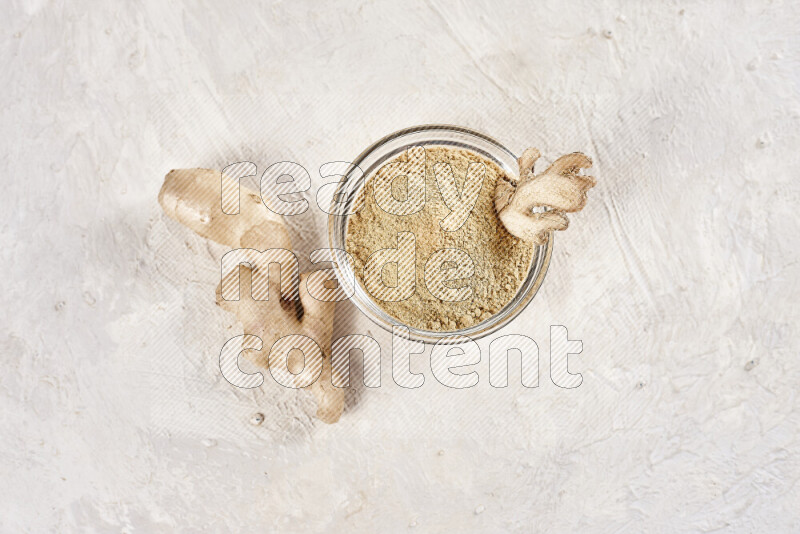 A glass bowl full of ground ginger powder on white background