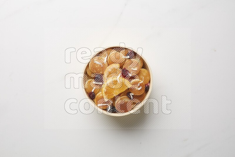 Top-view shot of orange candy cereal pancakes in a round bowl on white background
