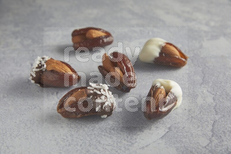 Group of Almonds stuffed dates plain and covered with chocolate on a light grey background