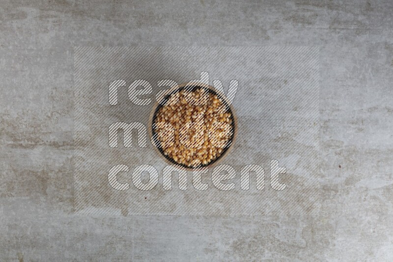 corn kernel in a wooden bowl on a grey textured countertop