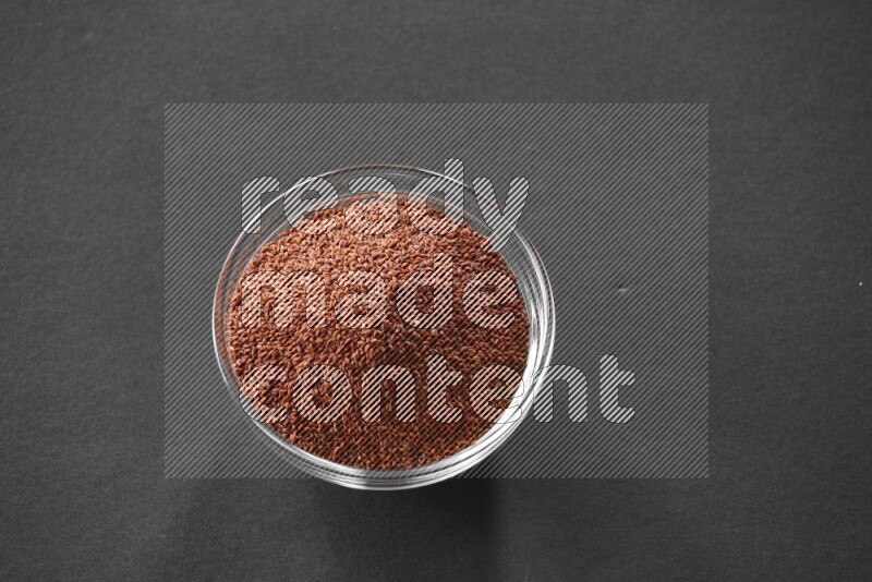 A glass bowl full of garden cress on black flooring