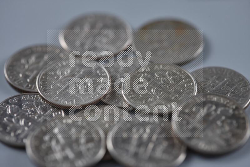 A close-up of scattered United States one dime coins on grey background