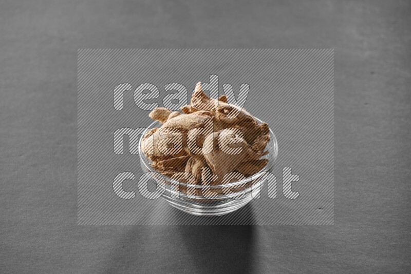 A glass bowl full of ginger on black flooring
